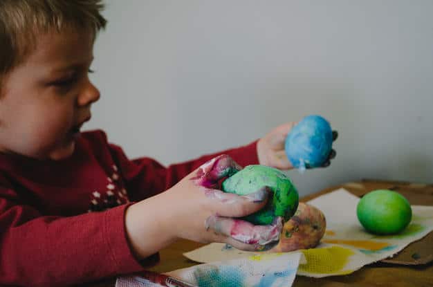 a child painting a boiled egg for Easter
