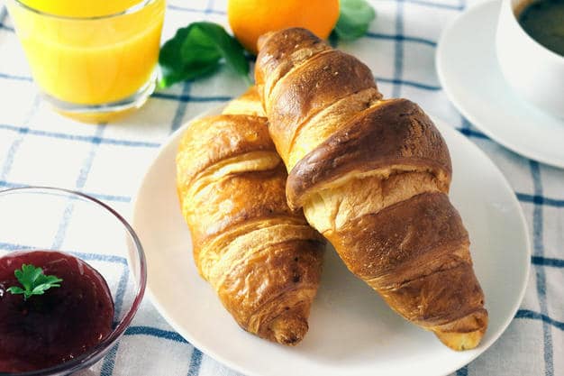 Croissants, jam, orange juice and coffee on a table